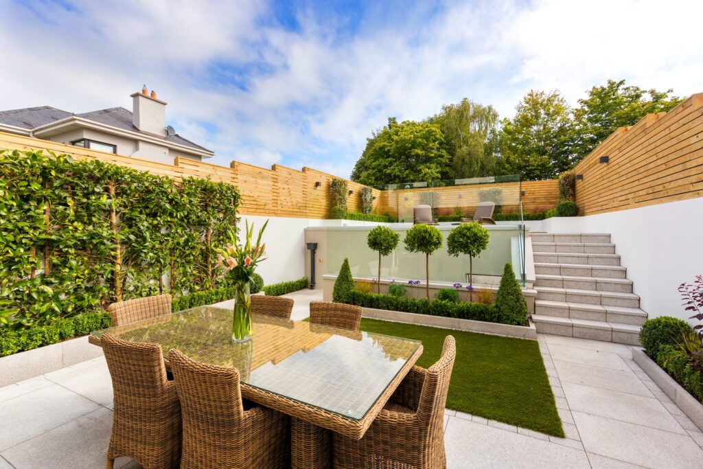 a patio with a table and chairs next to a fence